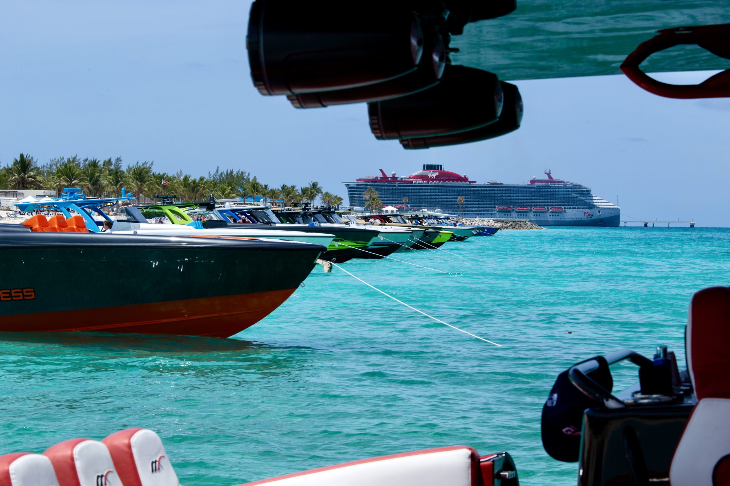 Boats anchored off Bimini in clear shallow water with a cruise ship at the pier behind them