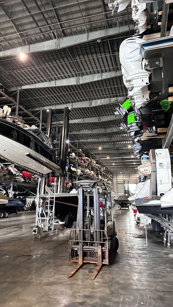 A forklift in the aisle of a covered dry stack building with boats racked on both sides