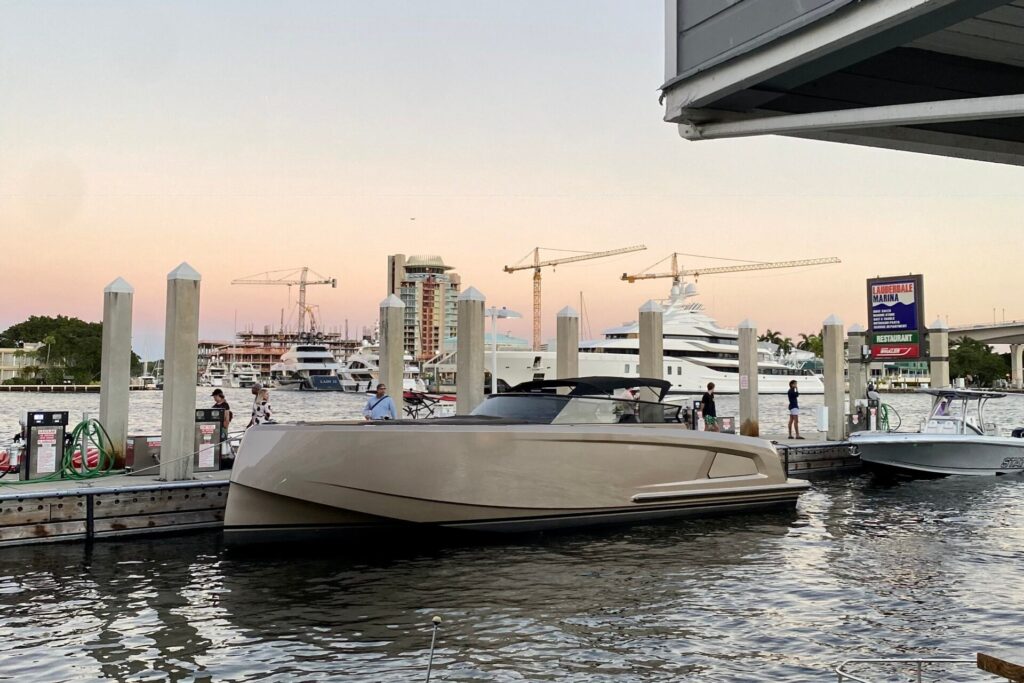 Boats in their slips at a South Florida marina at dusk with the skyline and cranes behind