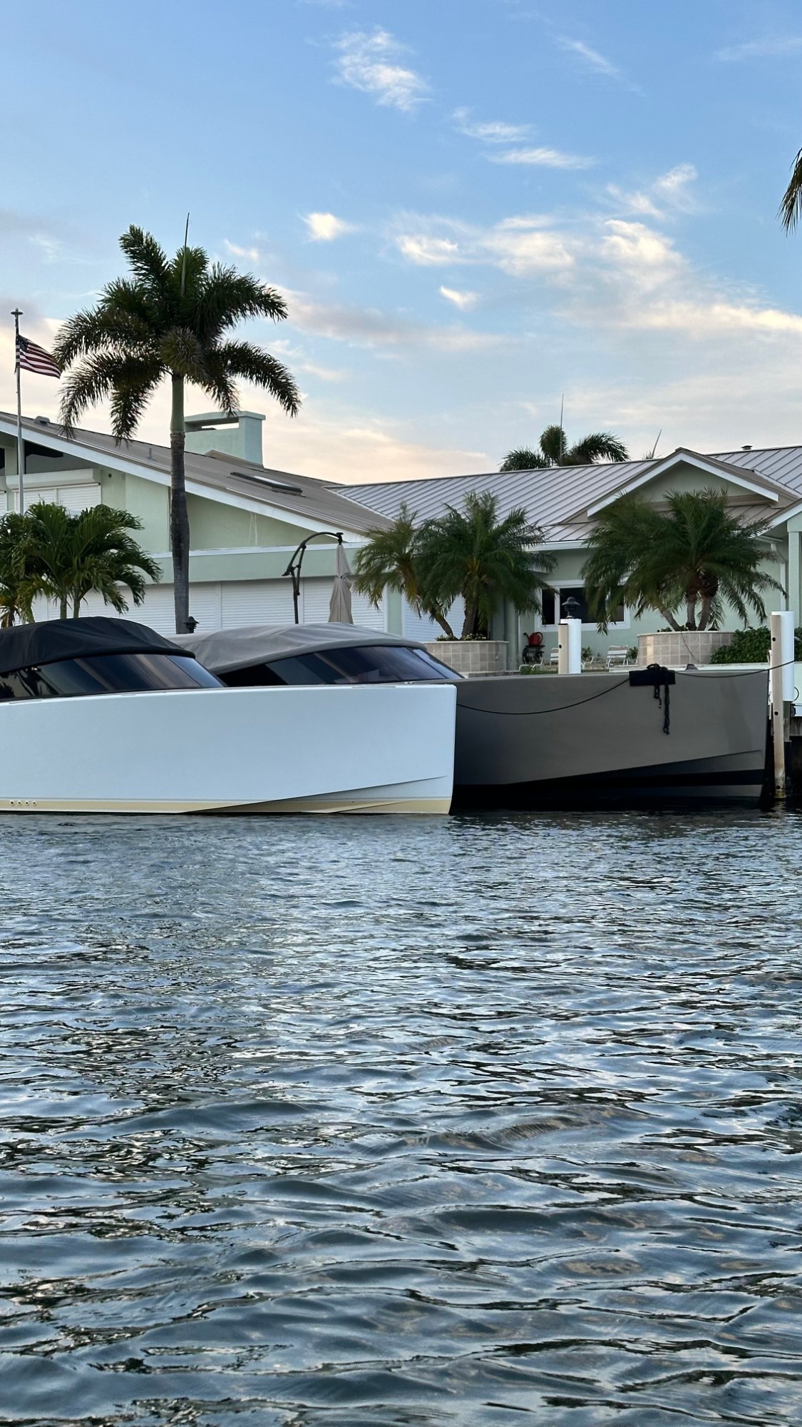 Two boats tied at a private dock behind a single story waterfront house on a South Florida canal