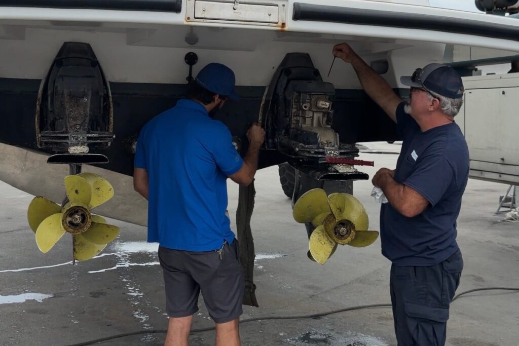 A surveyor and a broker examining the outdrives and propellers of a boat hauled out for a pre purchase survey